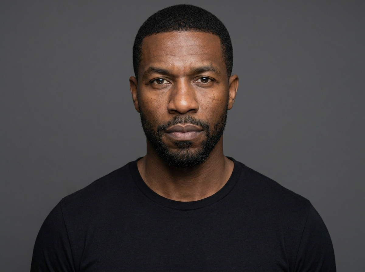 A controlled identity portrait of Dr. Elias Mercer against a charcoal background. He faces the camera with a calm, guarded expression. Restrained gold interface marks identify him as Individual 001 and the confirmed successor.